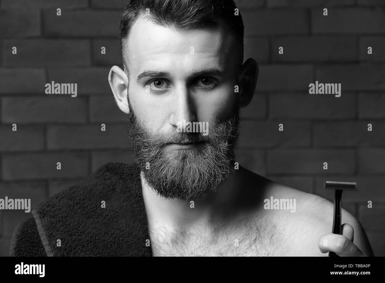 Bearded man with razor against brick wall Stock Photo Alamy