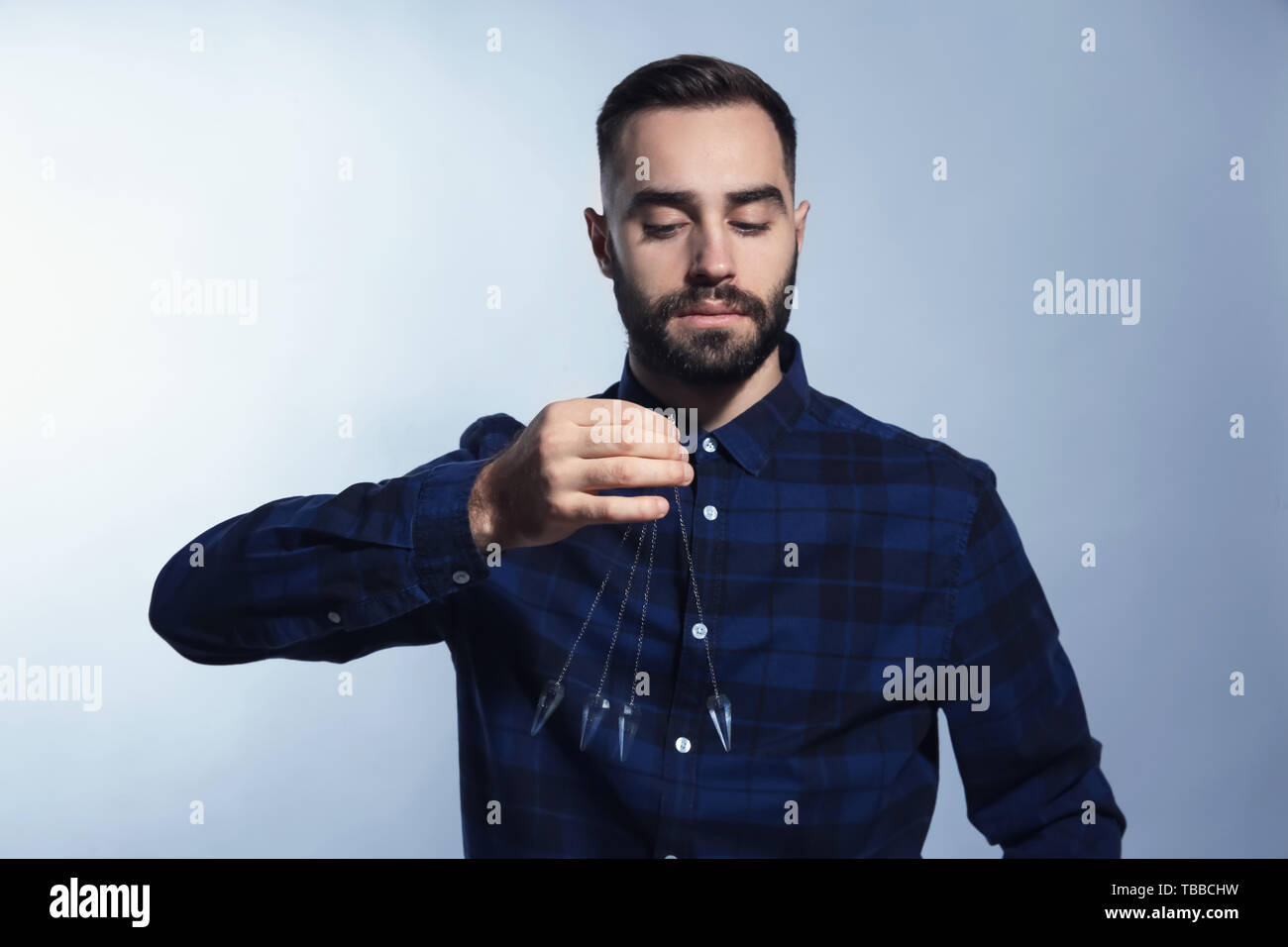 Male hypnotist with swinging pendulum on grey background Stock Photo ...