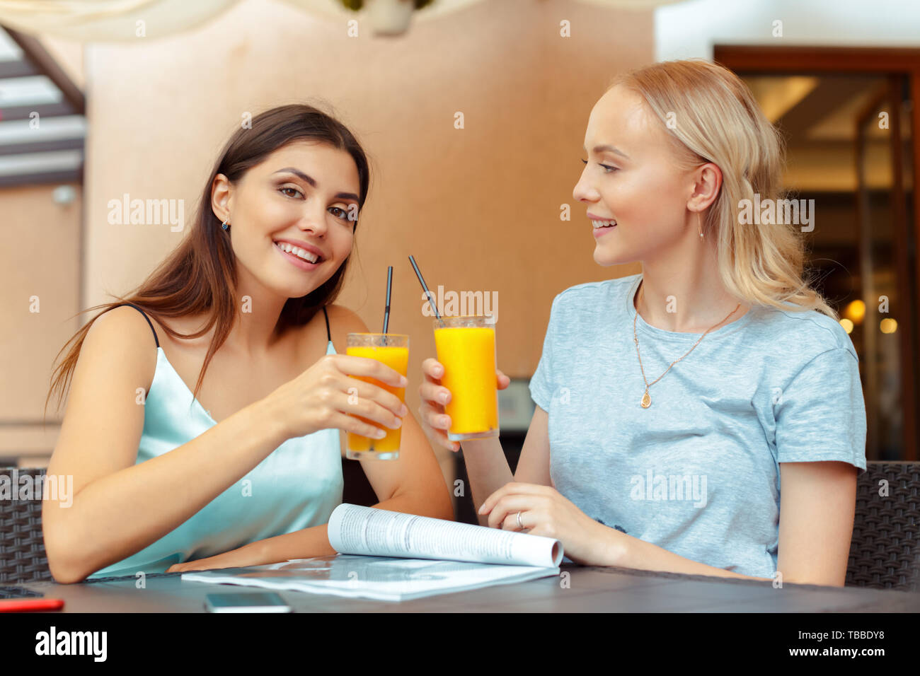 Two beautiful young girls sitting by the table in cafe Stock Photo - Alamy