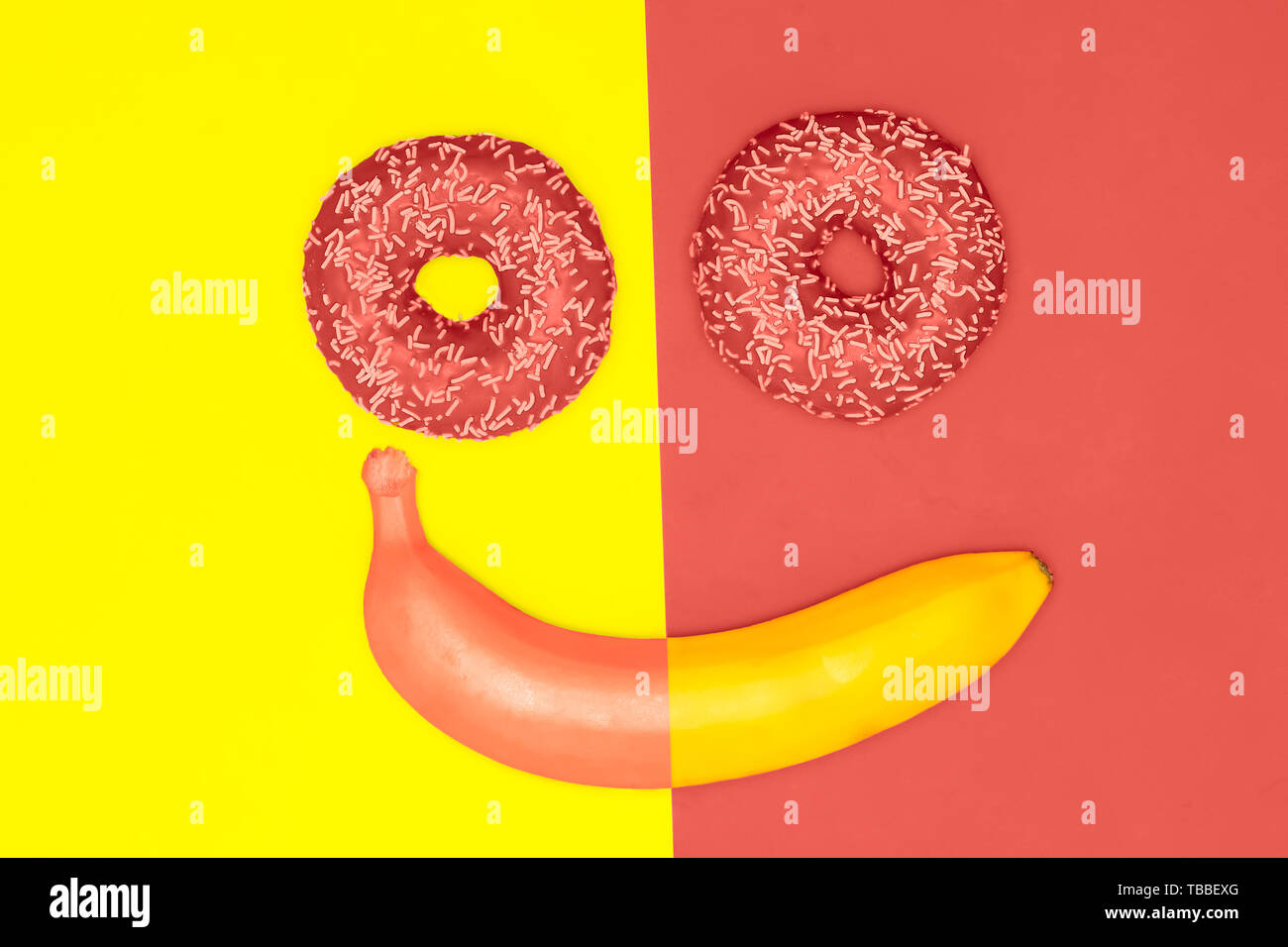 Good mood, smiles food concept. Donuts and a banana in the form of a smiling face. Living coral flat lay Stock Photo