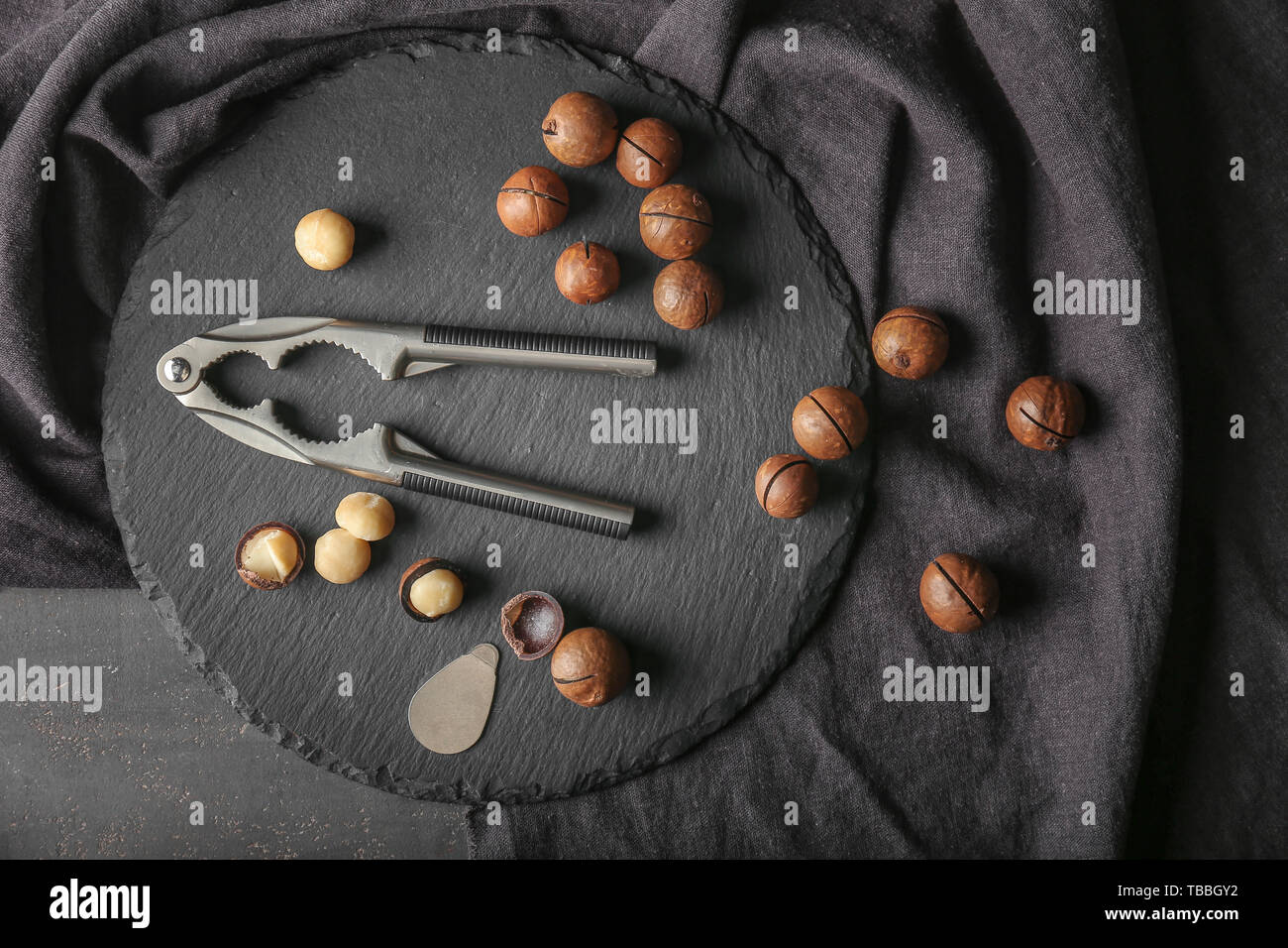 Macadamia nuts with nutcracker on slate plate Stock Photo Alamy