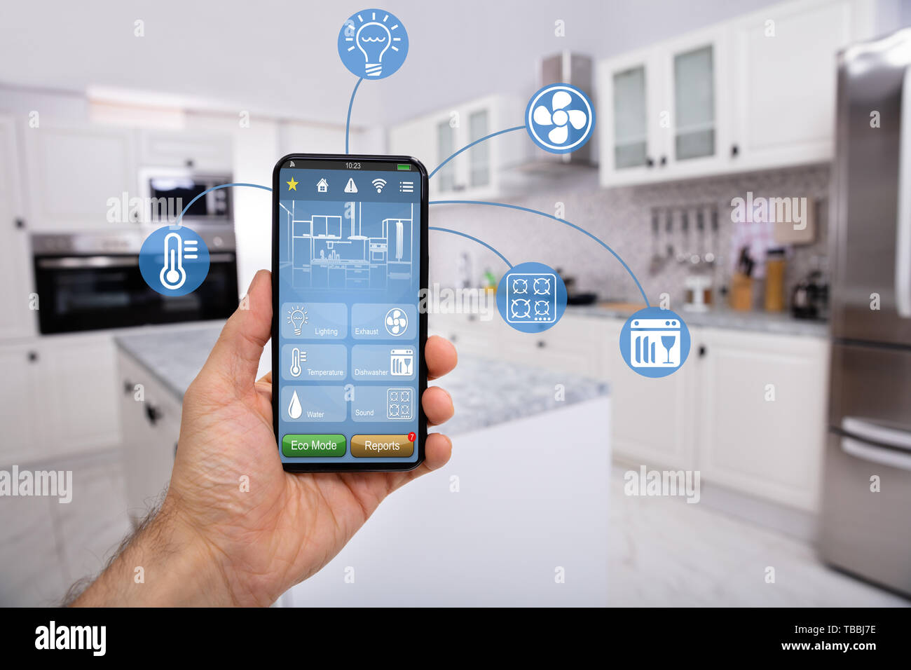 Close-up Of Man's Hand Holding Mobile With Smart Home Control Icon Feature With Kitchen Background Stock Photo