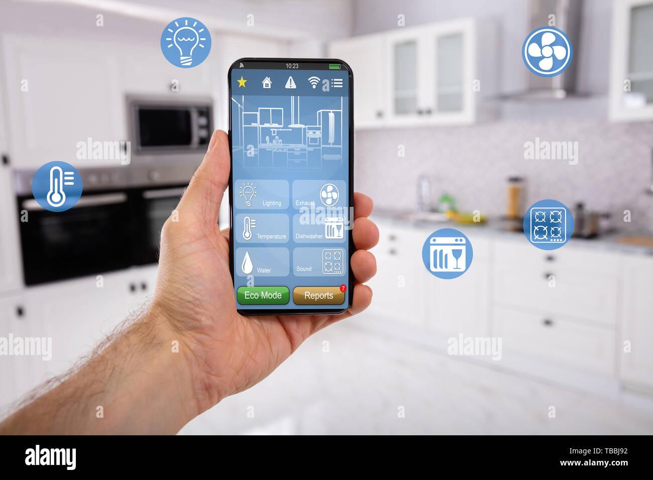Close-up Of Man's Hand Holding Mobile With Smart Home Control Icon Feature With Kitchen Background Stock Photo