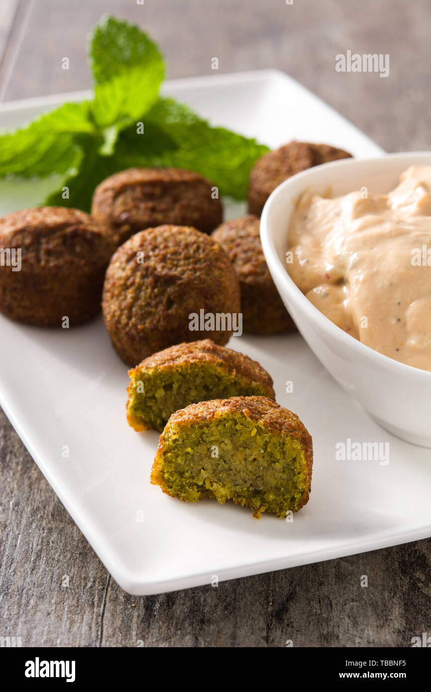 Falafel on a plate and tahini sauce on wooden table. Stock Photo
