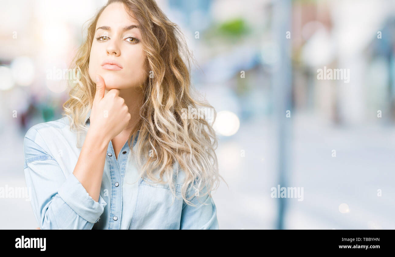 Beautiful young blonde woman over isolated background looking confident ...
