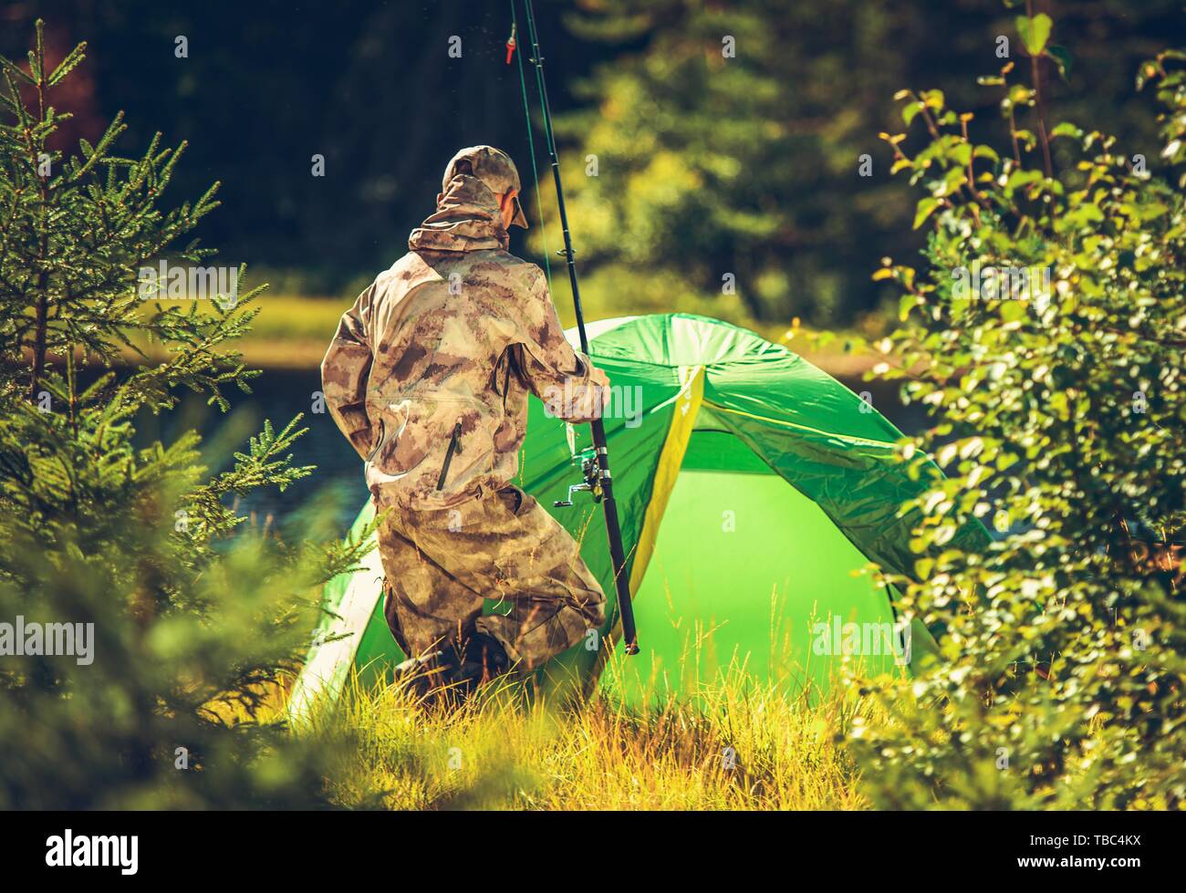 Fly Fishing Camp in a Wilderness. Caucasian Men with Fishing Rod in Hand in Front of His Tent. Closeup Photo. Stock Photo