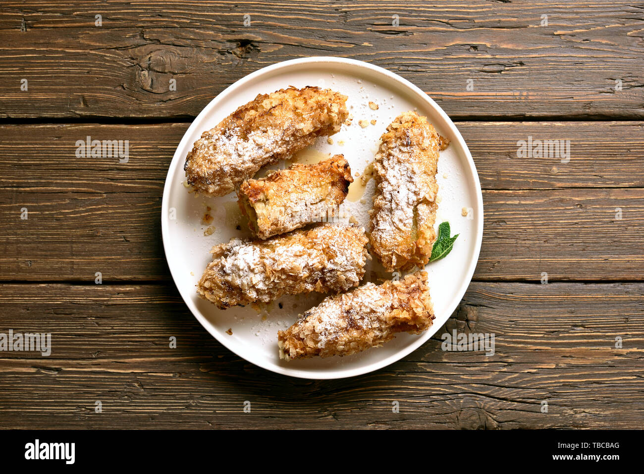 Deep fried bananas on plate over wooden background. Tasty dessert from