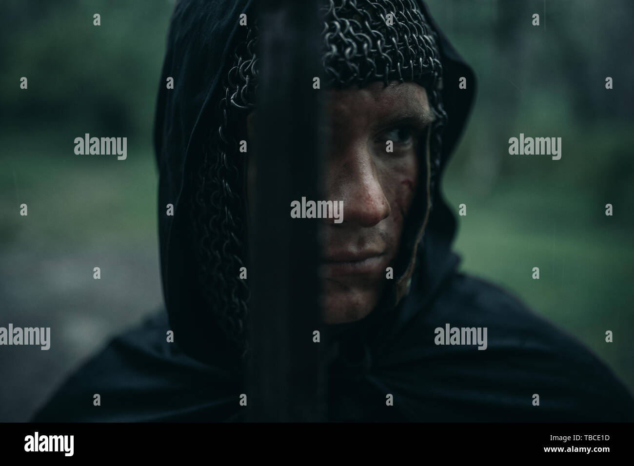 Portrait of young man in the image of a medieval knight in chain armor ...