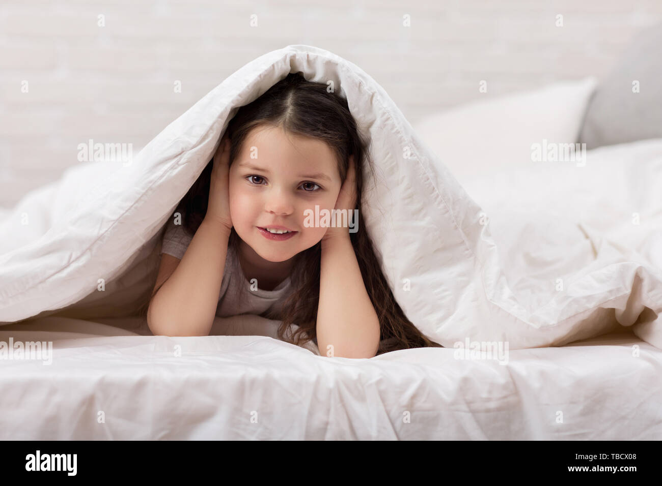 happy morning baby in bed. child dabbles in bed. child covers his ears