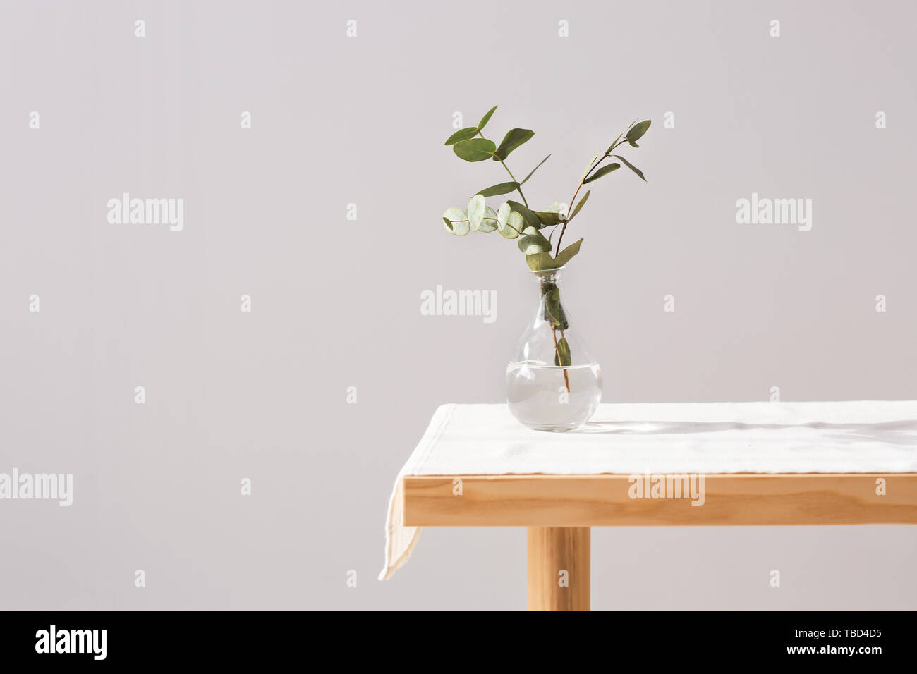 Vase with fresh eucalyptus branches on table against grey background Stock Photo