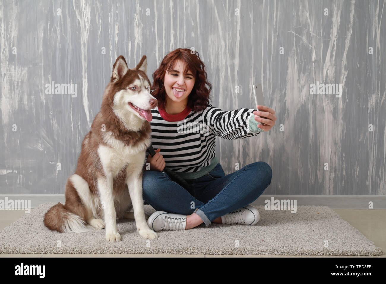 Young woman taking selfie with her cute dog near grey wall Stock Photo ...