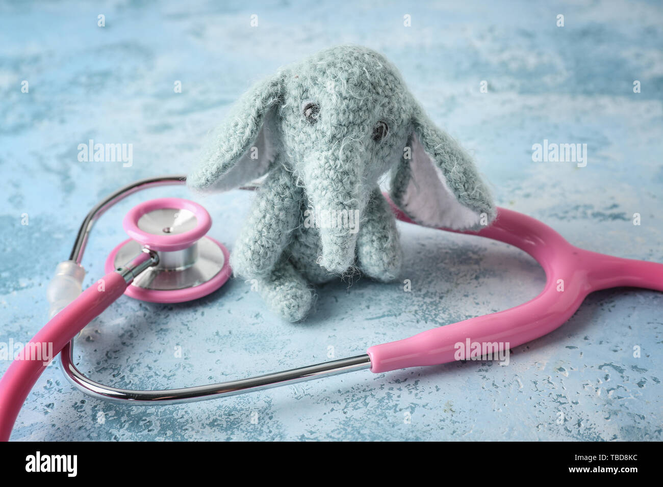 Cute elephant toy with stethoscope on color background. Health care for
