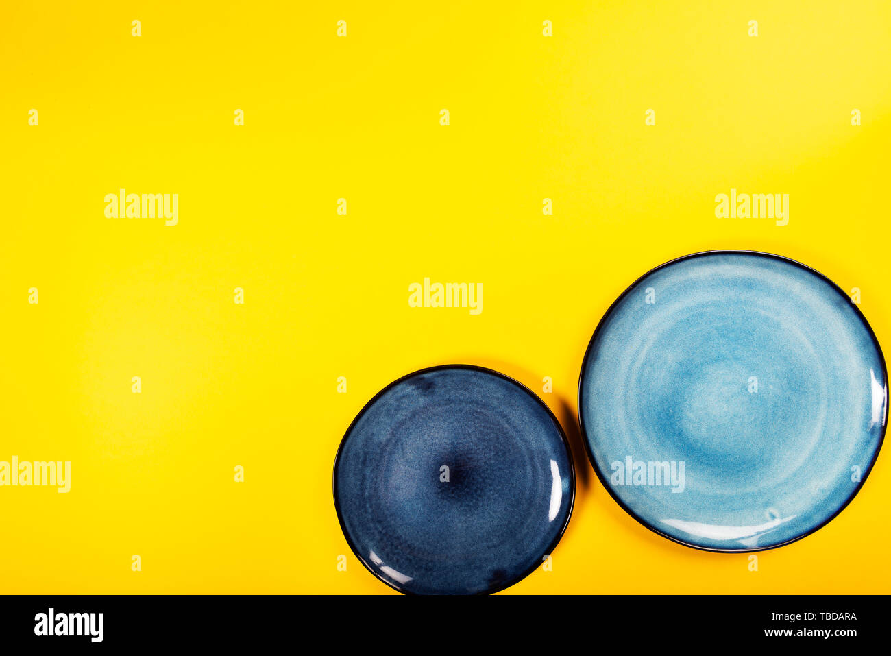 Empty Blue Plates on Bright Yellow Background, Top View, Copy Space Stock Photo