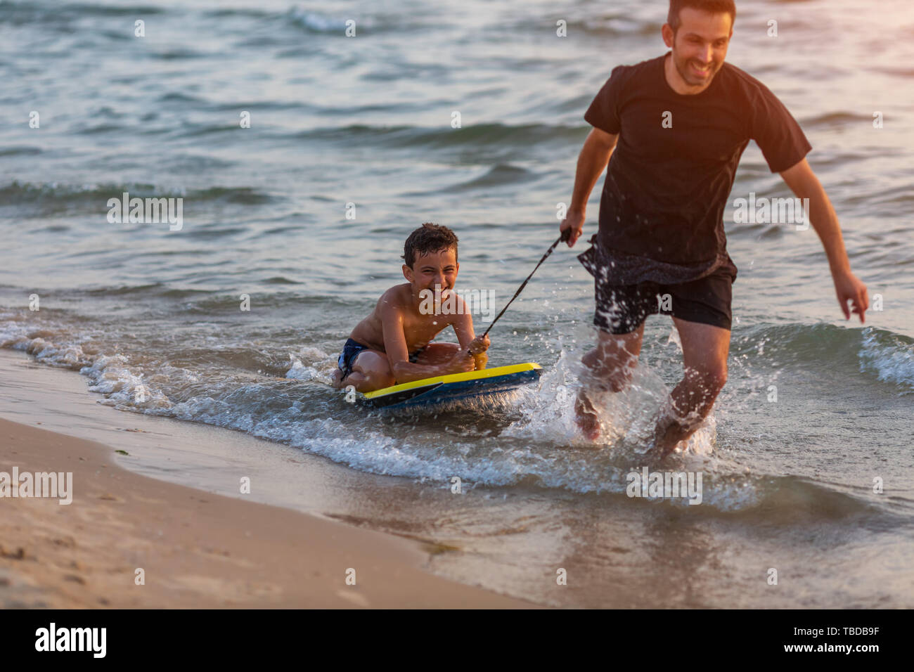 Father and son surfing on boogie boards on the sunset Stock Photo Alamy