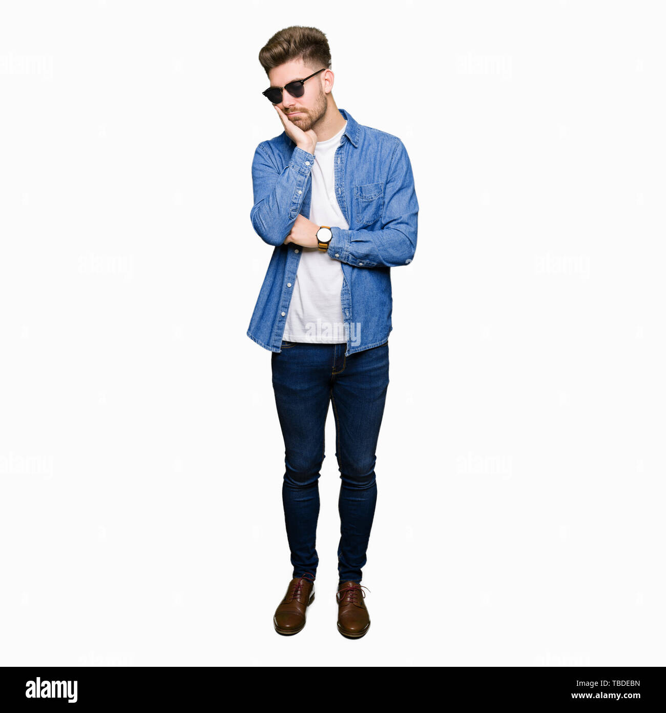 Young handsome elegant man wearing denim jacket thinking looking tired and bored with depression problems with crossed arms. Stock Photo