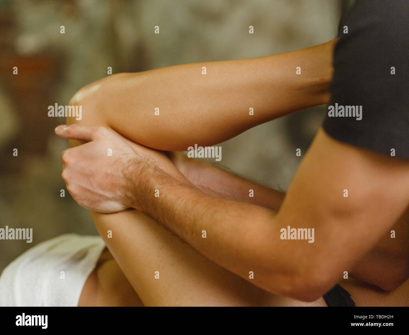 Extreme close up of osteopath applying pressure with thumb on female calf muscle. close up, blur, bokeh Stock Photo