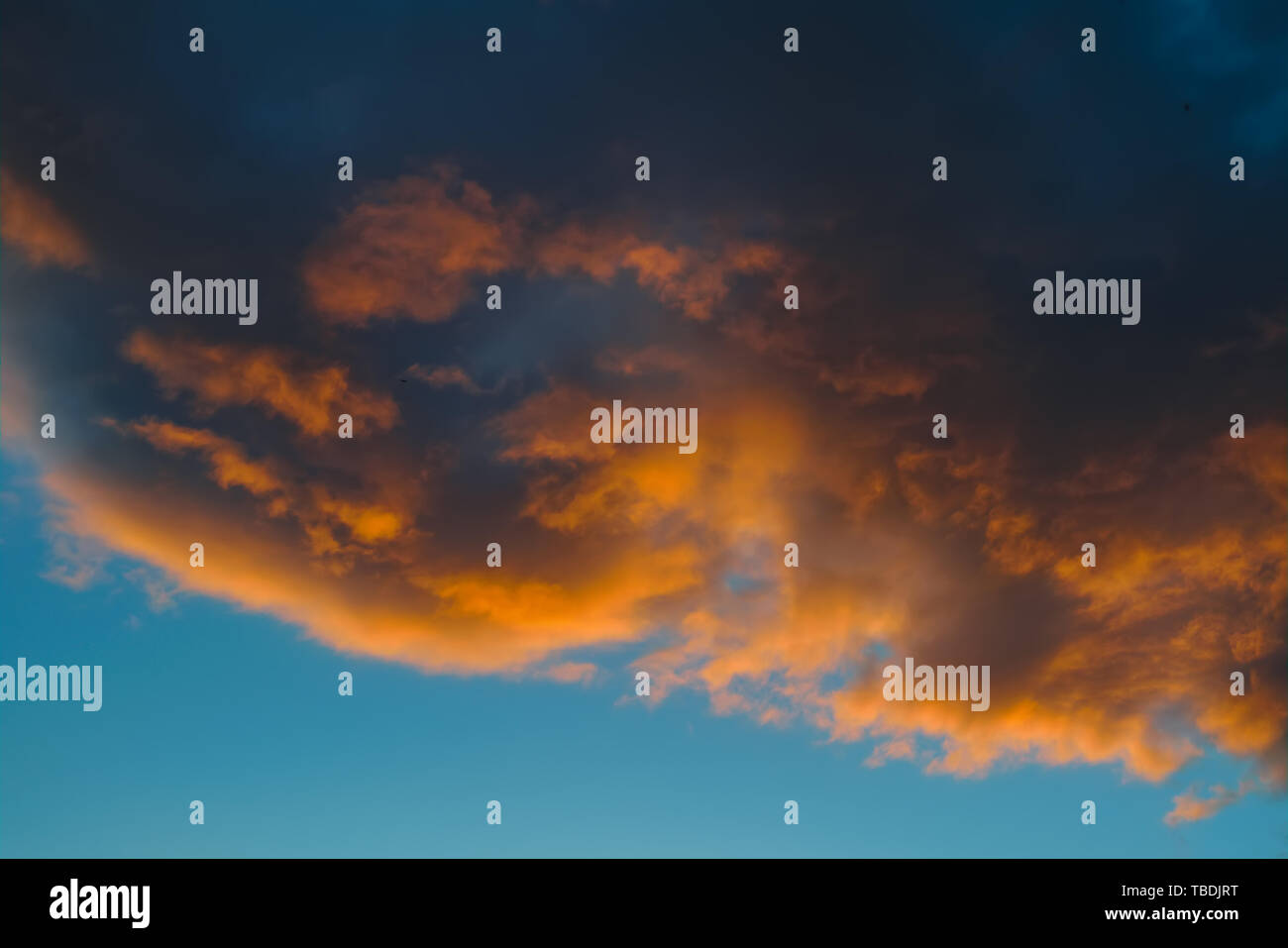 Dramatic evening sky with beautiful clouds illuminated by the setting sun. Stock Photo