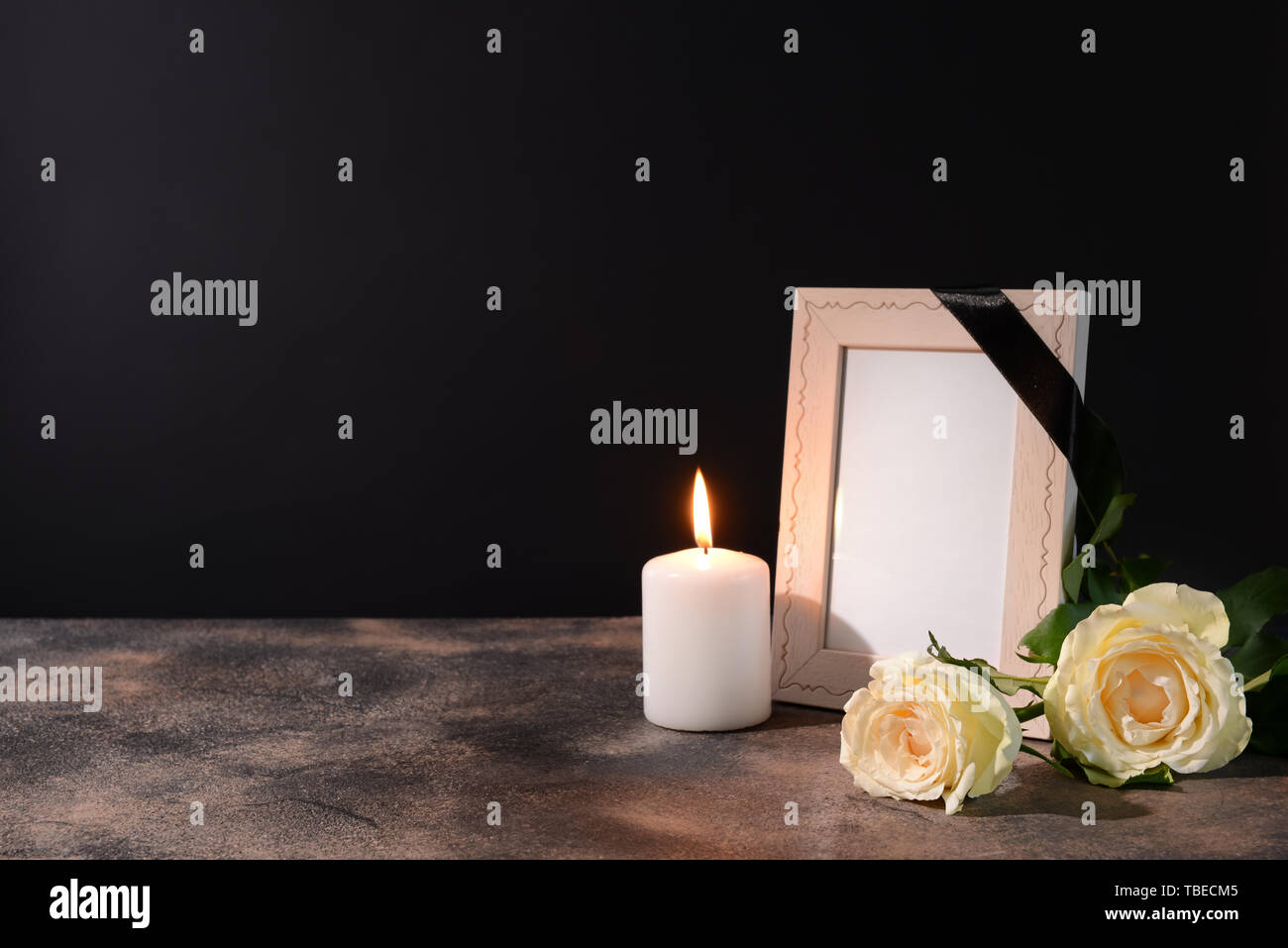 Blank funeral frame, candle and flowers on table against black background  Stock Photo - Alamy