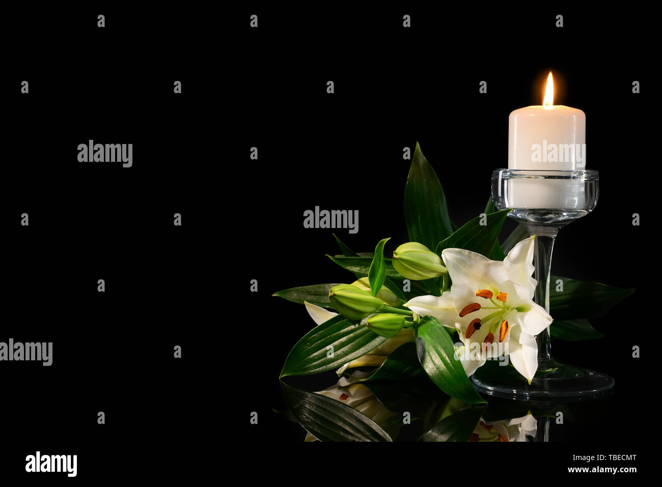 Burning candle and flowers on black background Stock Photo