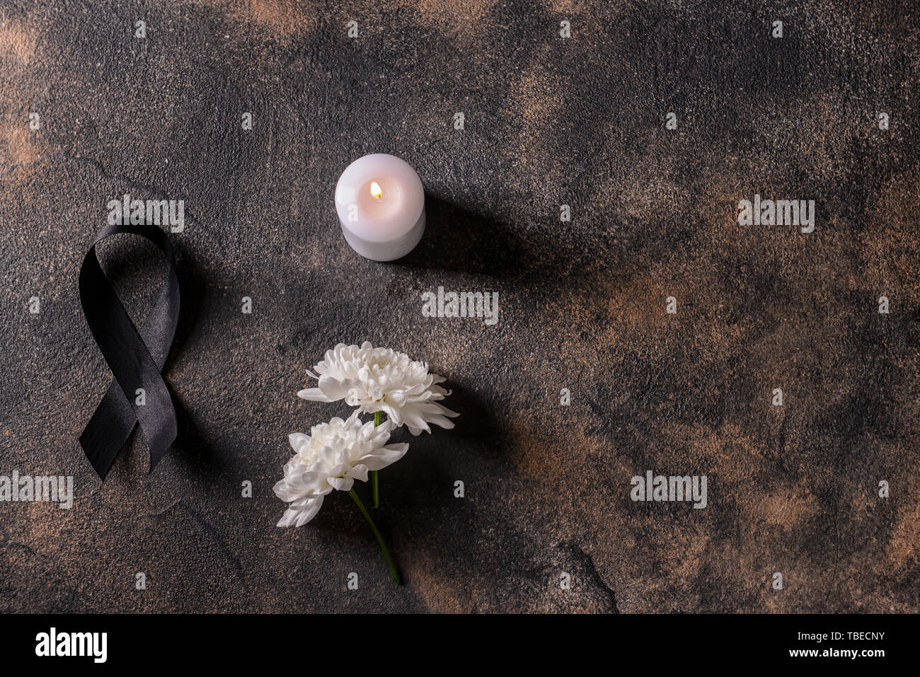 Black mourning ribbon, flowers and candle on grunge background Stock Photo