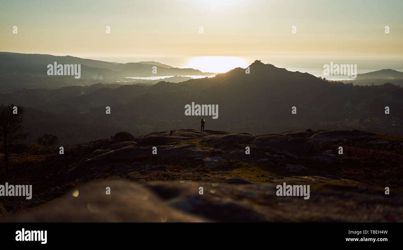 Silhouette of a person contemplating an enormous landscape from Mount Galiñeiro in Vigo, Spain Stock Photo