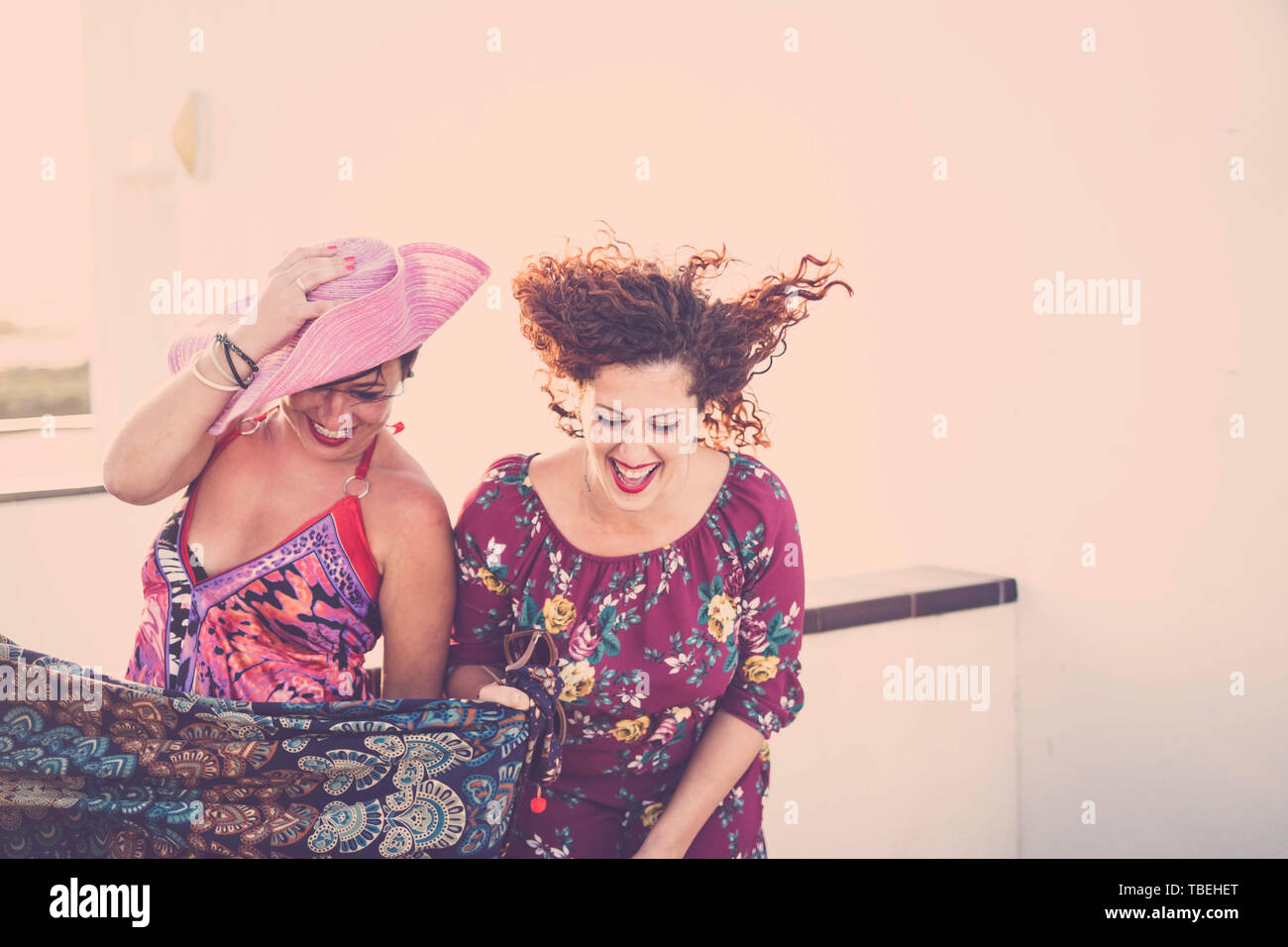 Crazy and cheerful couple of young caucasian women friends laugh a lot - people having fun outdoor in coloured party festival - bright clear backgroun Stock Photo