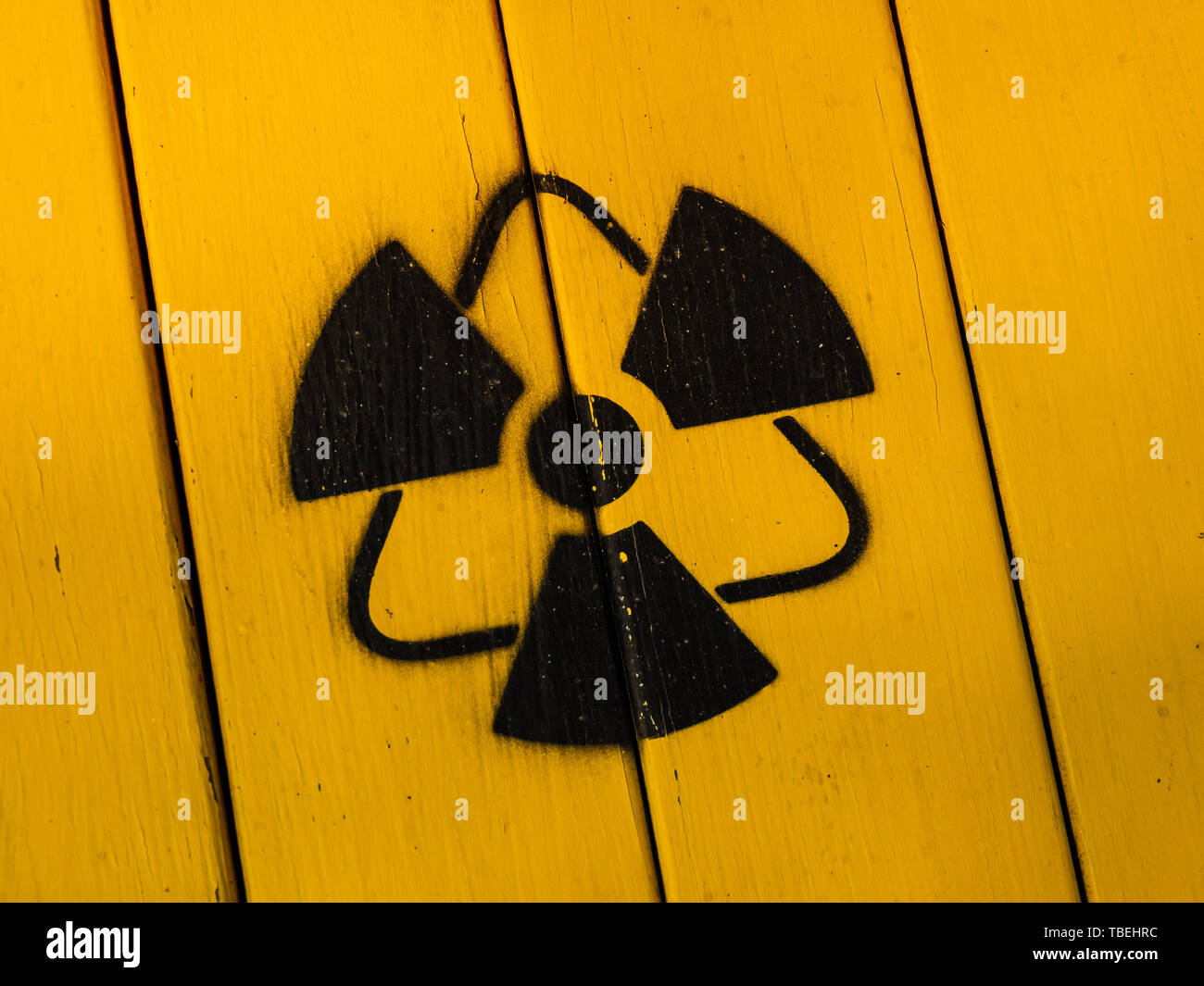 Radioactivity sign, close-up. Sign of radiation on a yellow wooden board. Radioactive sign - symbol of radiation. Yellow and black radioactive hazard, Stock Photo