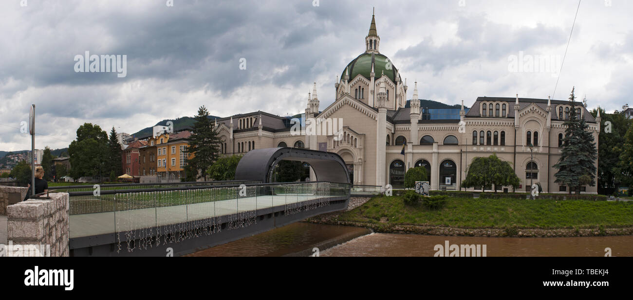 Sarajevo: the Festina lente bridge with its looping in the middle, over Miljacka River, and the palace of the Academy of Fine Arts, public university Stock Photo