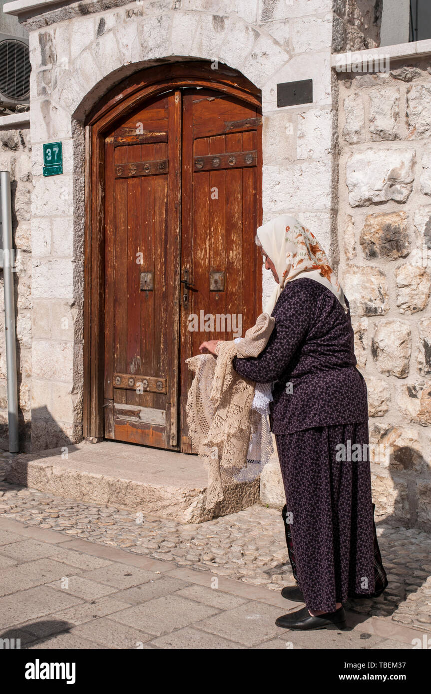 Sarajevo: elderly Bosnian lady selling hand-embroidered tablecloths and doilies in Bascarsija square, the old bazaar and historical center of the city Stock Photo