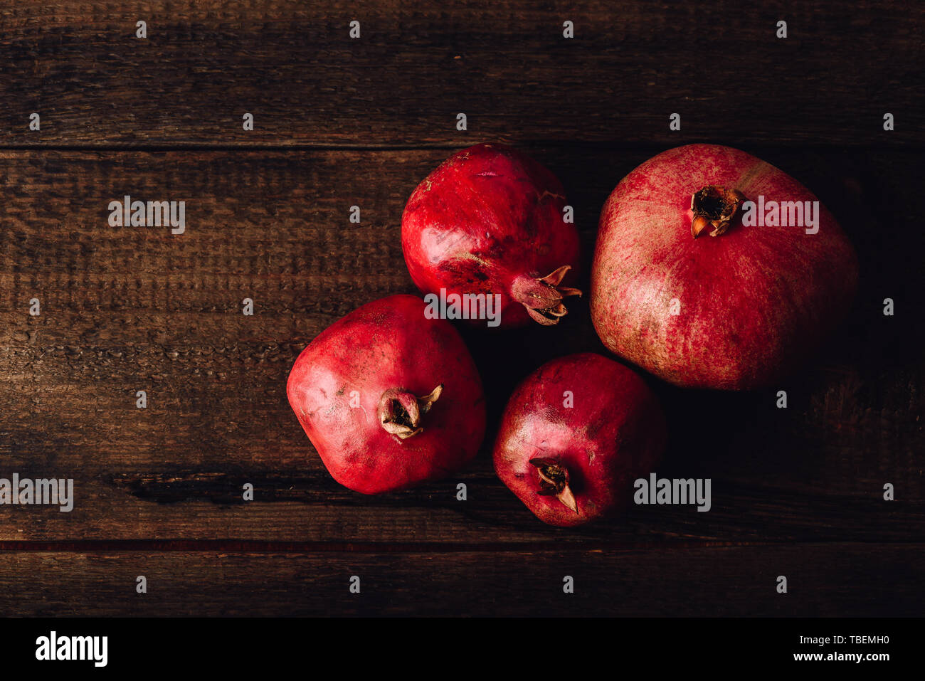 Four ripe pomegranate on rustic wooden table Stock Photo
