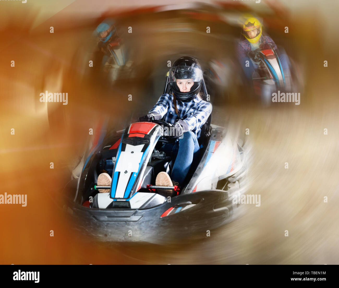 Group of glad positive smiling people driving go-carts at racing track ...