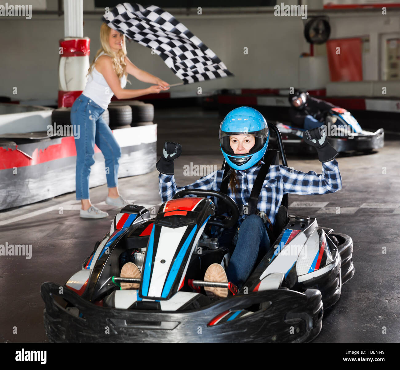 Pretty adult female go-cart racer crossing finish line Stock Photo - Alamy