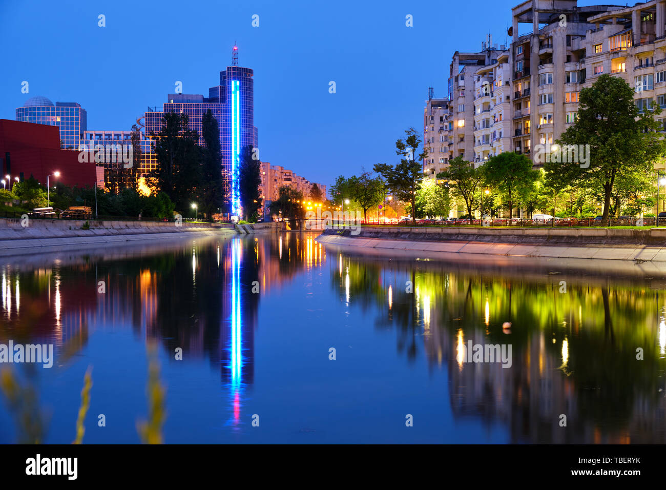 Blue hour light reflections in the city, on Dambovita river, in Bucharest, Romania. Tall building Chamber of Commerce and Industry of Romania in cente Stock Photo