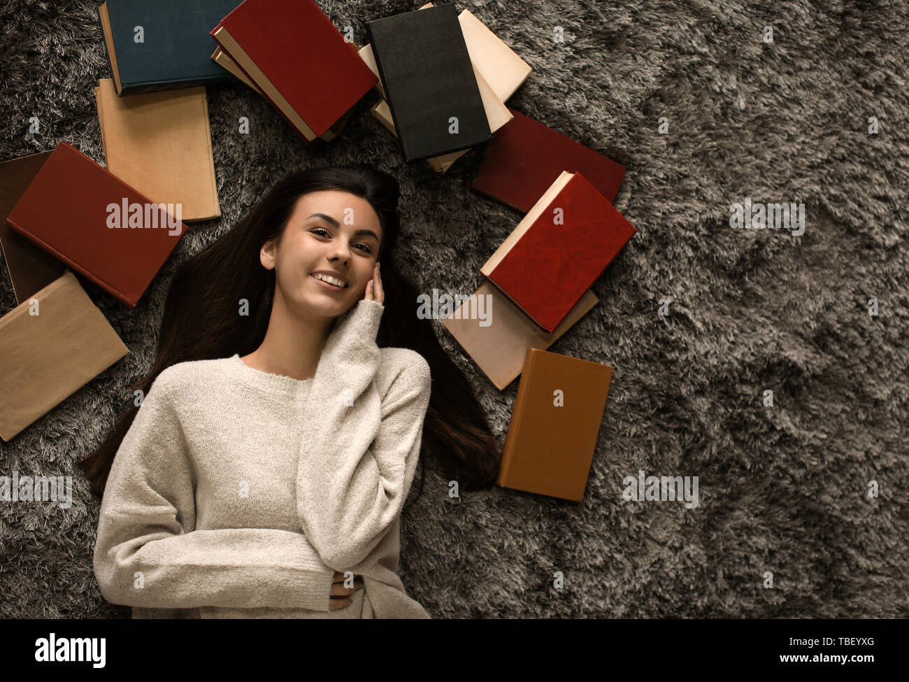 Portrait of beautiful young woman with books lying on floor Stock Photo ...