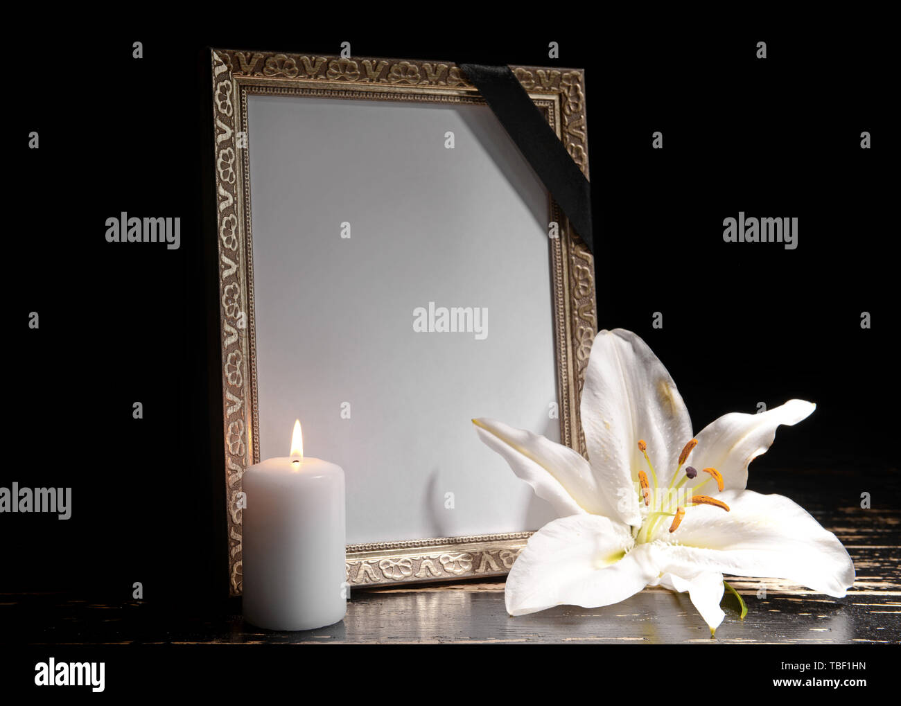 Blank Funeral Frame Burning Candle And Flower On Table Against