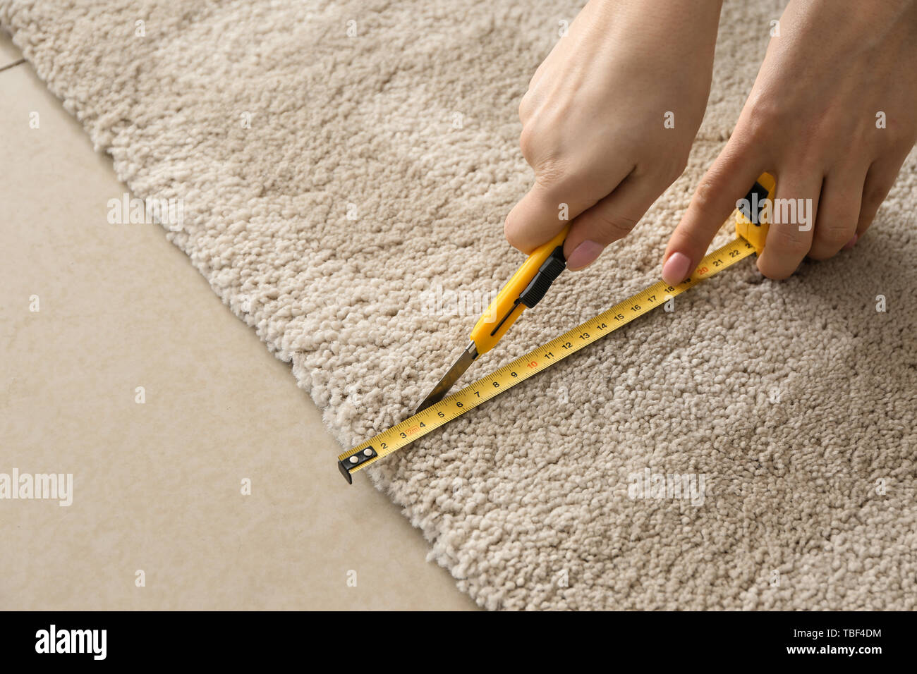 Woman with tape measure cutting carpet Stock Photo Alamy