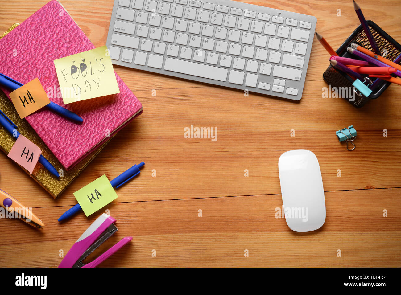 Computer keyboard with stationery and sticky notes on wooden background