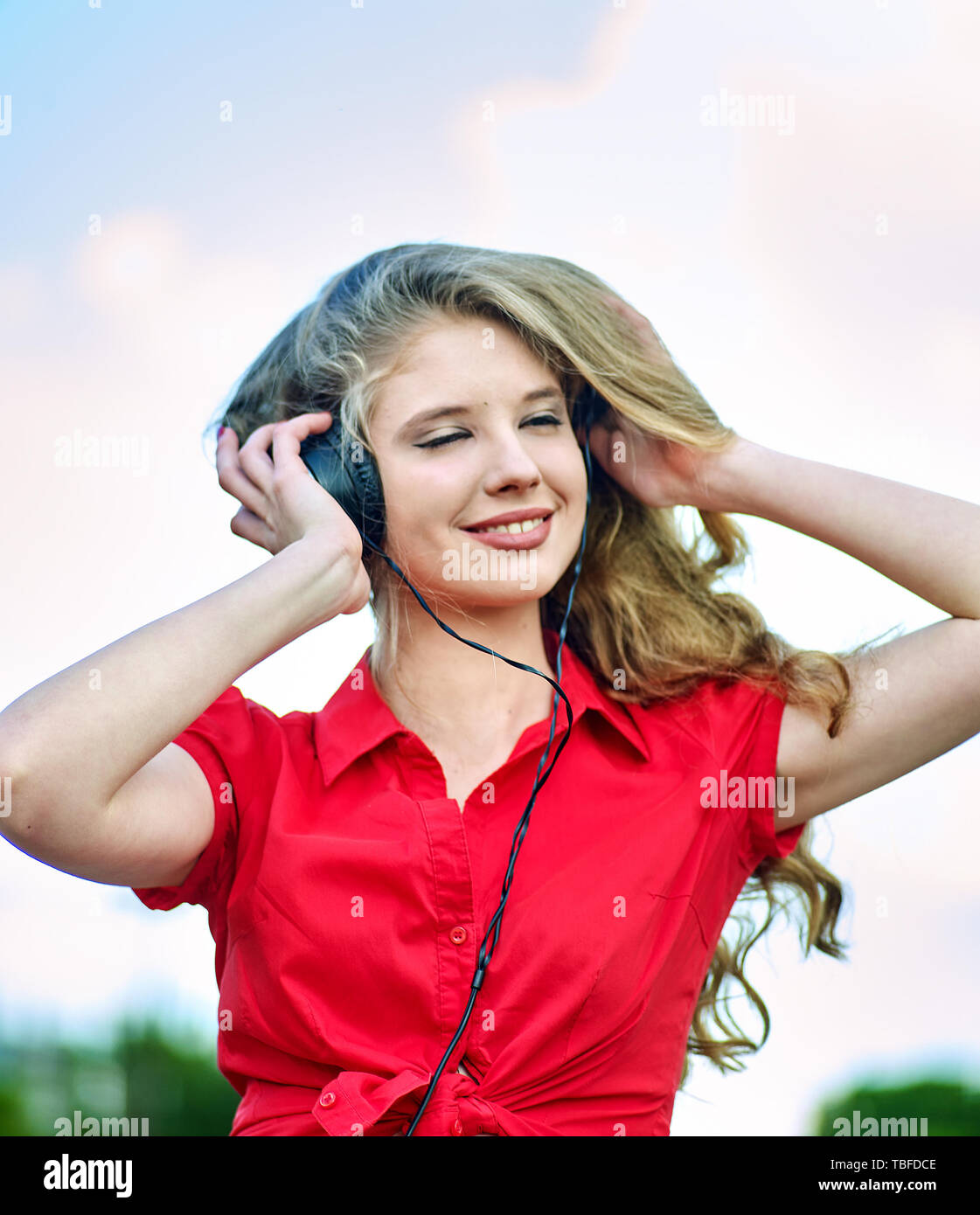 Student girl with backpack in headphone listen music after exam. Time to relaxing on sun flare morning sunrays in green park nature. Walking improves  Stock Photo