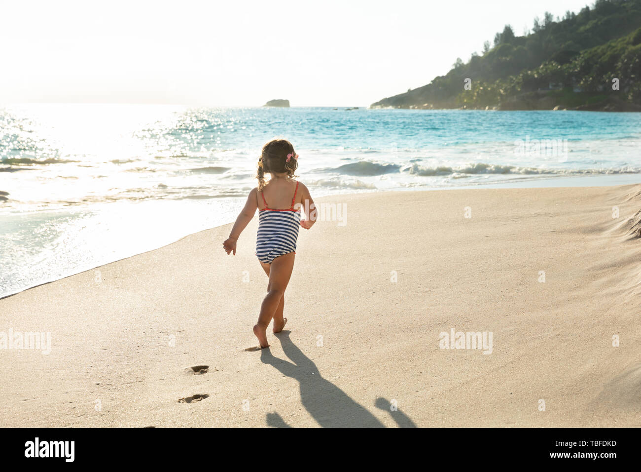 Rear View Of A Toddler Girl In Swimsuit Walking In Sand At Beach Stock ...