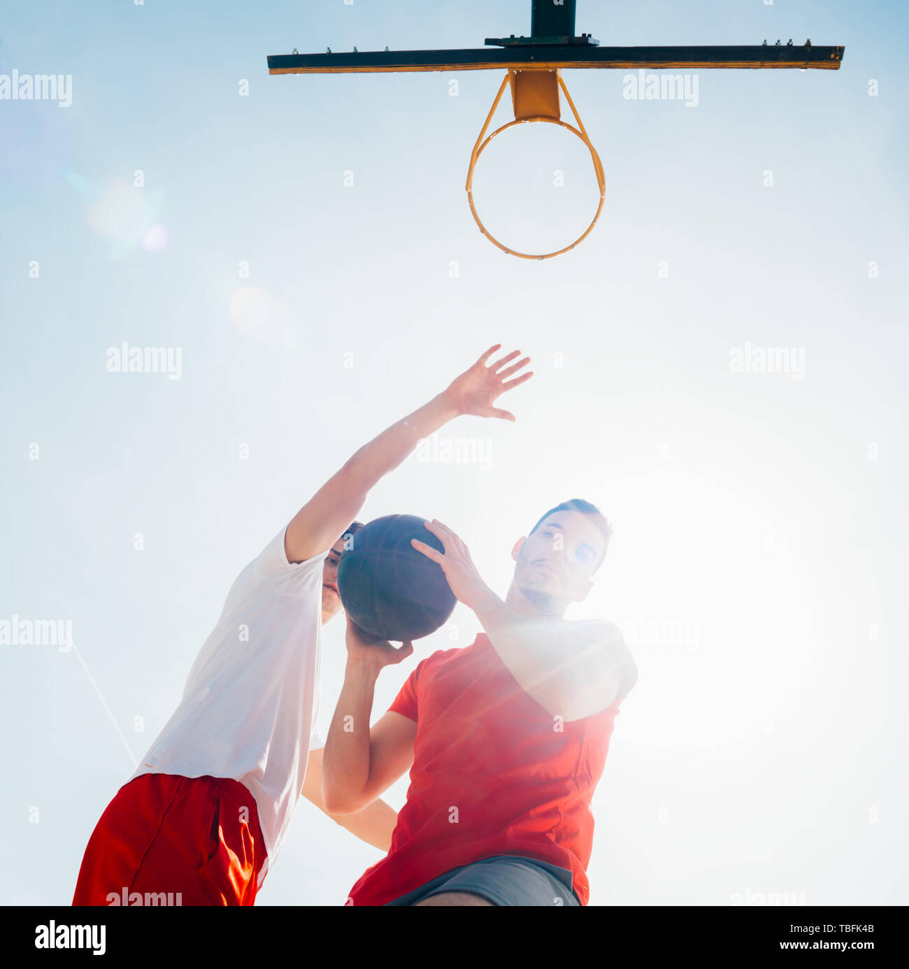 Two strong male basketball players play ball out doors fighting for a