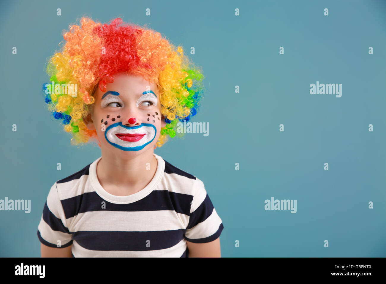 Cute little boy with clown makeup on color background. April fools' day