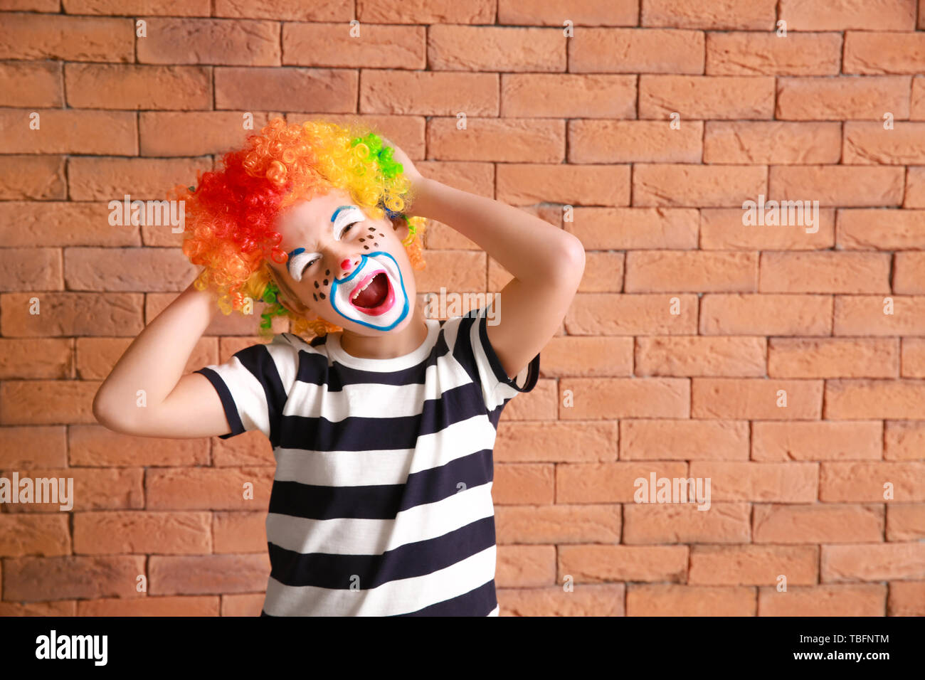 Cute little boy with clown makeup against brick wall. April fools' day  celebration Stock Photo - Alamy