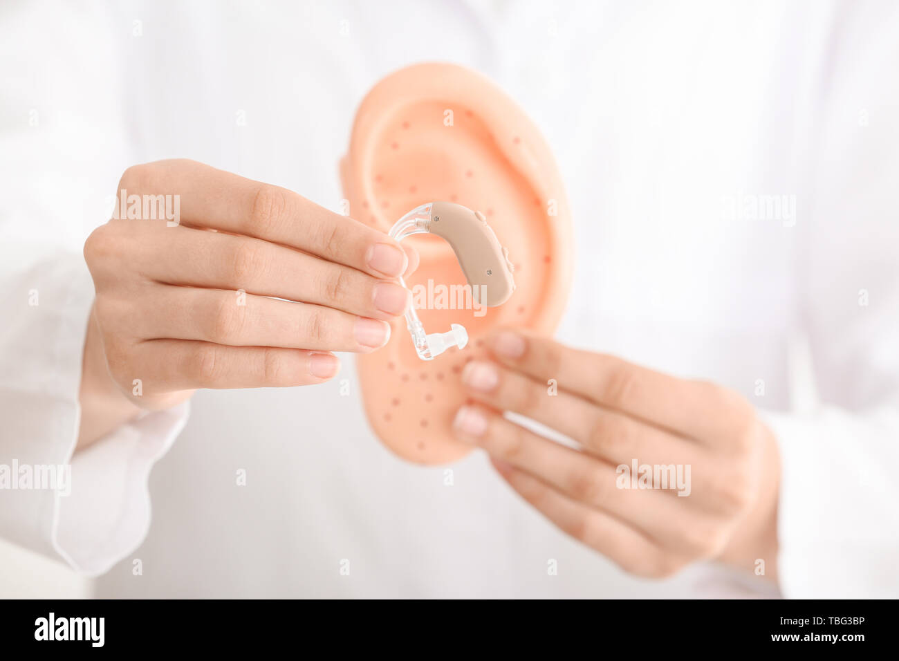 Female doctor with hearing aid and model of ear, closeup Stock Photo