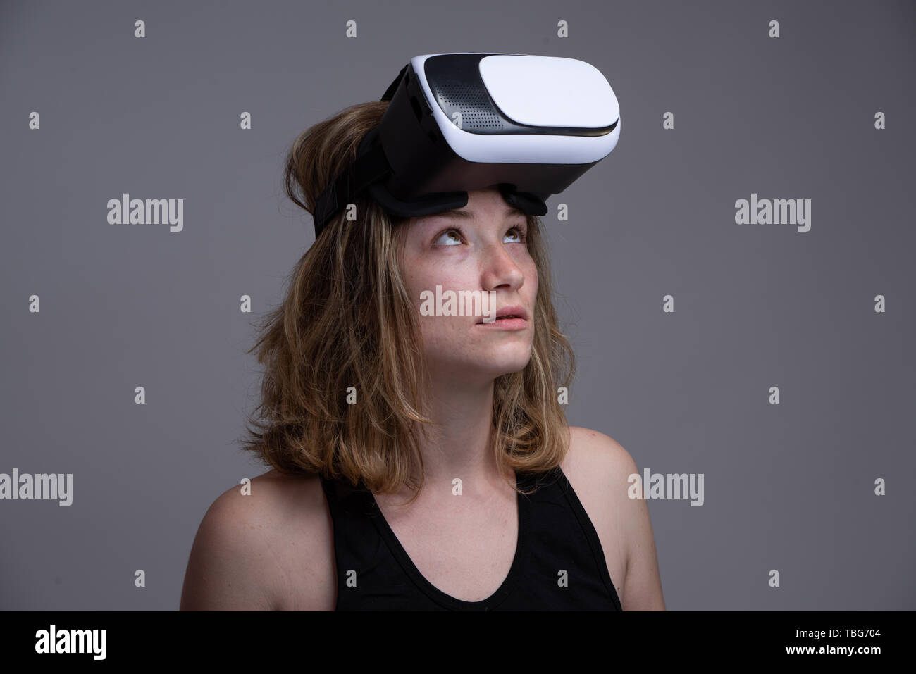 Girl making funny faces while holding on her head a 3D VR wearable ...