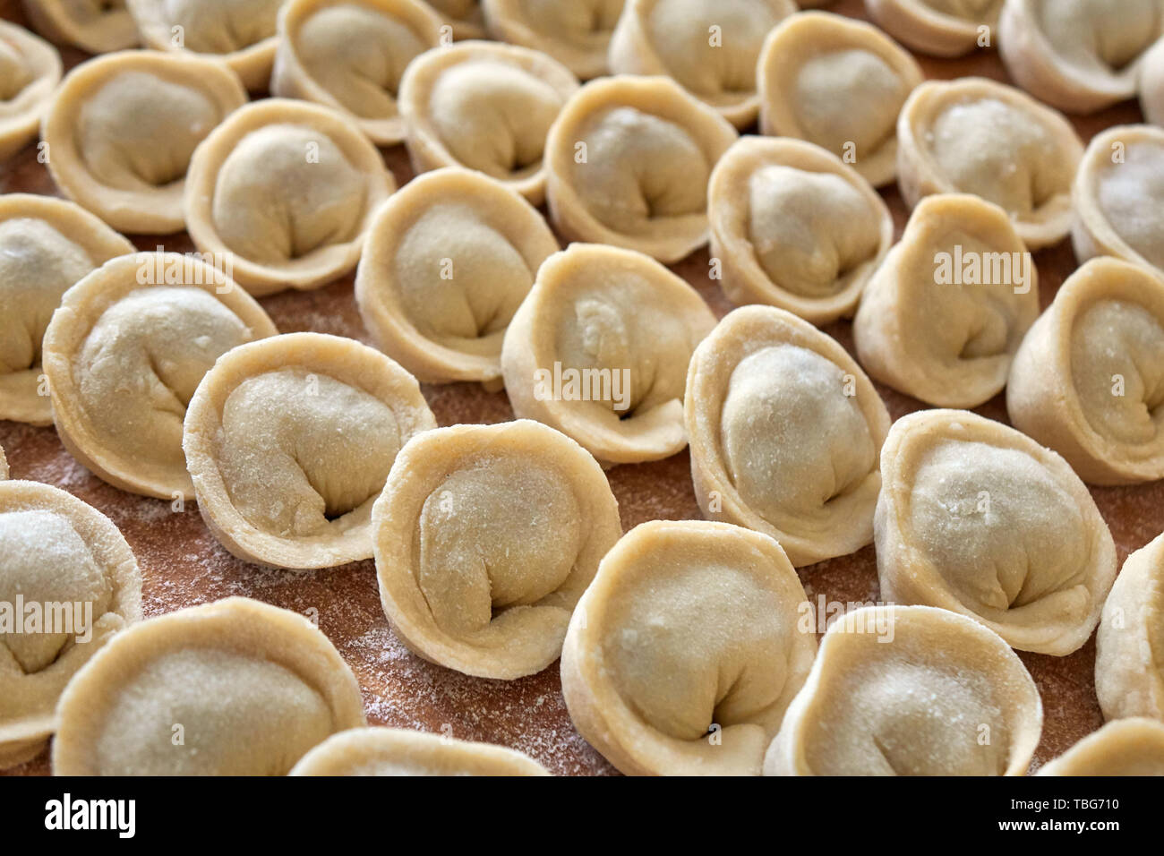 Homemade russian dumplings, pelmeni, covered in flour on the wooden board Stock Photo