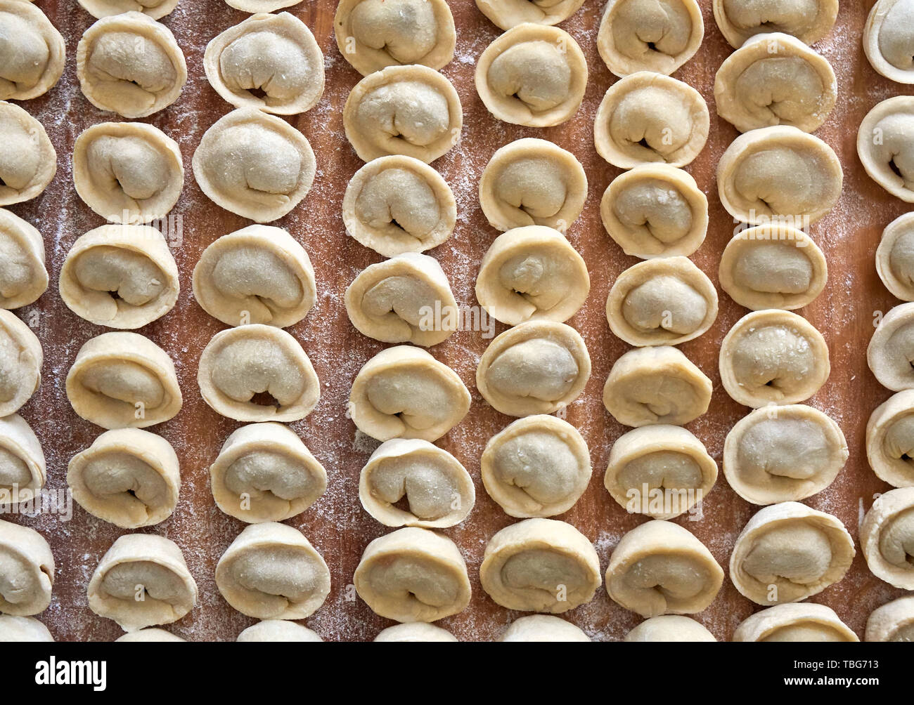 Homemade russian dumplings, pelmeni, covered in flour on the wooden board Stock Photo