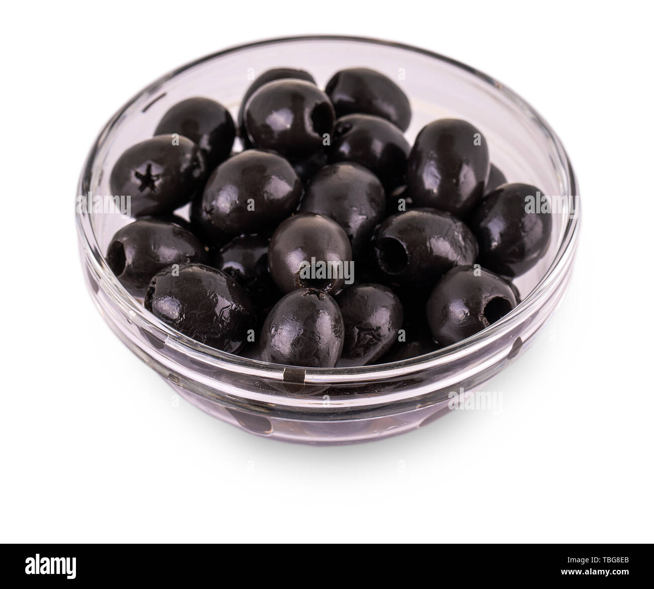 Black Olives without pits lie in a glass cup on the white background