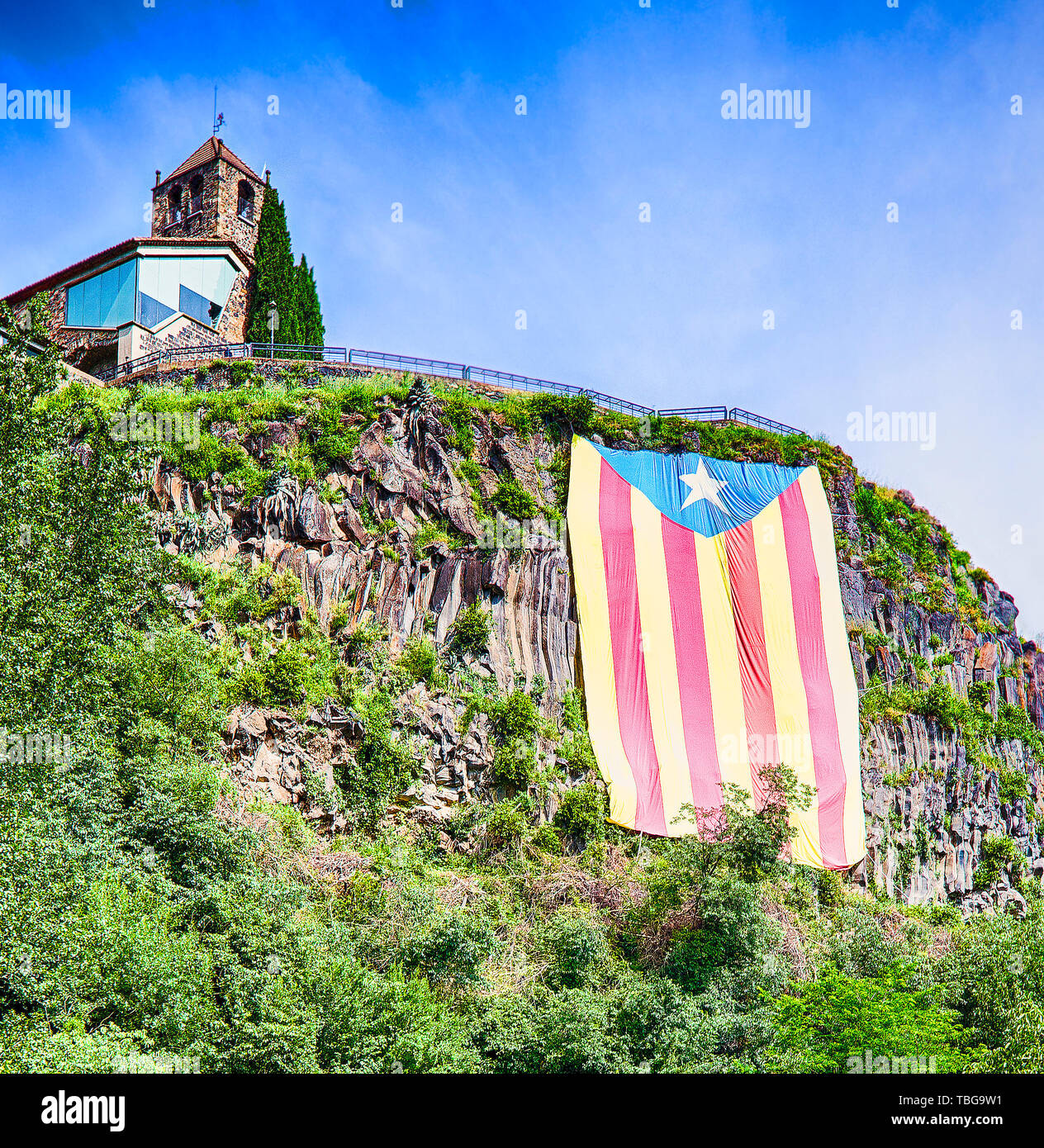 Castellfullit de la Roca, Spain - 15 JUNE 2018:  Large sunlit Catalan flag on the rock against a blue sky Stock Photo