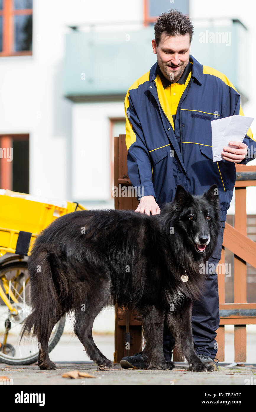 Big black dog welcoming postman at garden gate Stock Photo