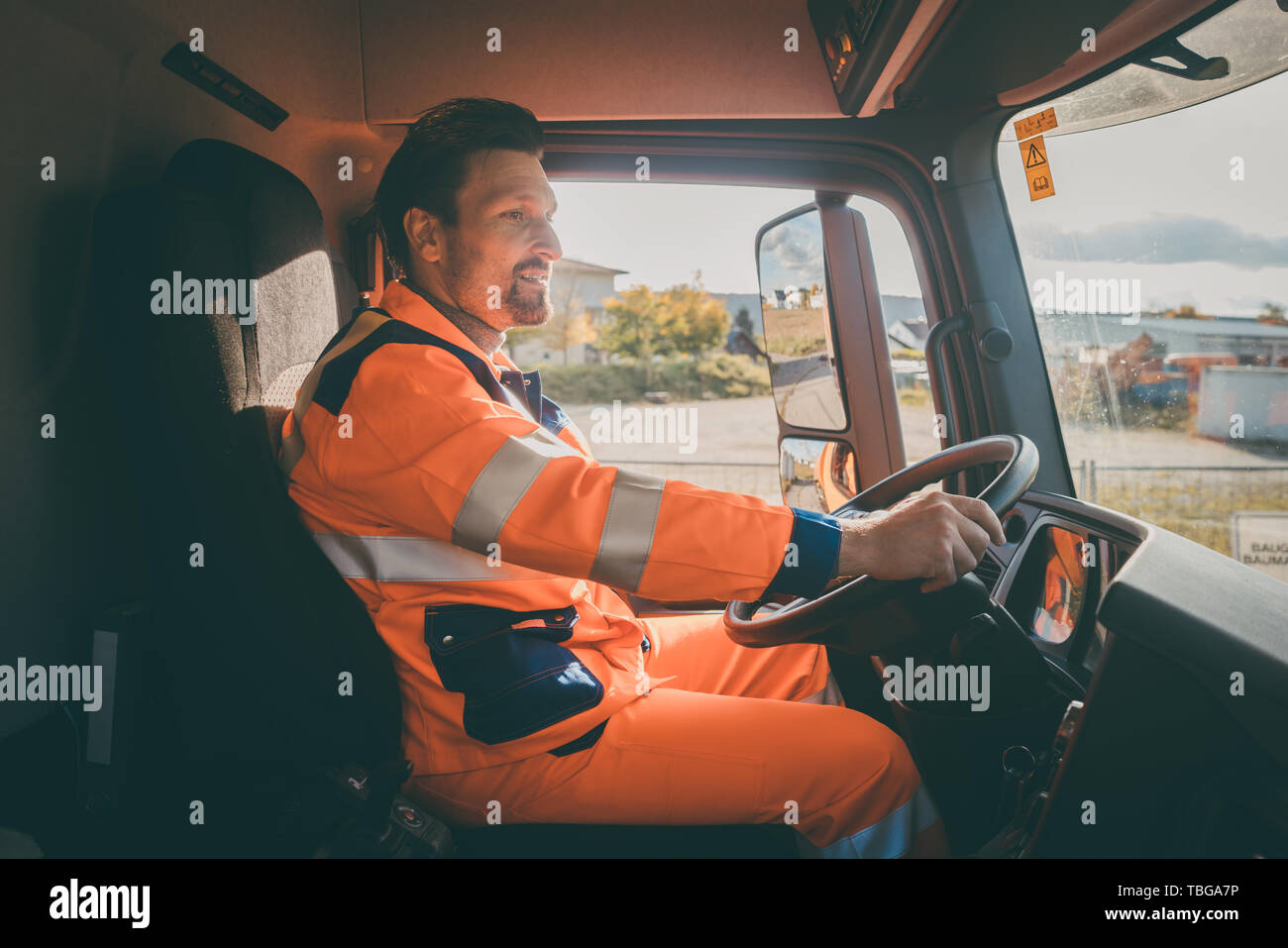 Garbage removal worker driving a dump truck  Stock Photo